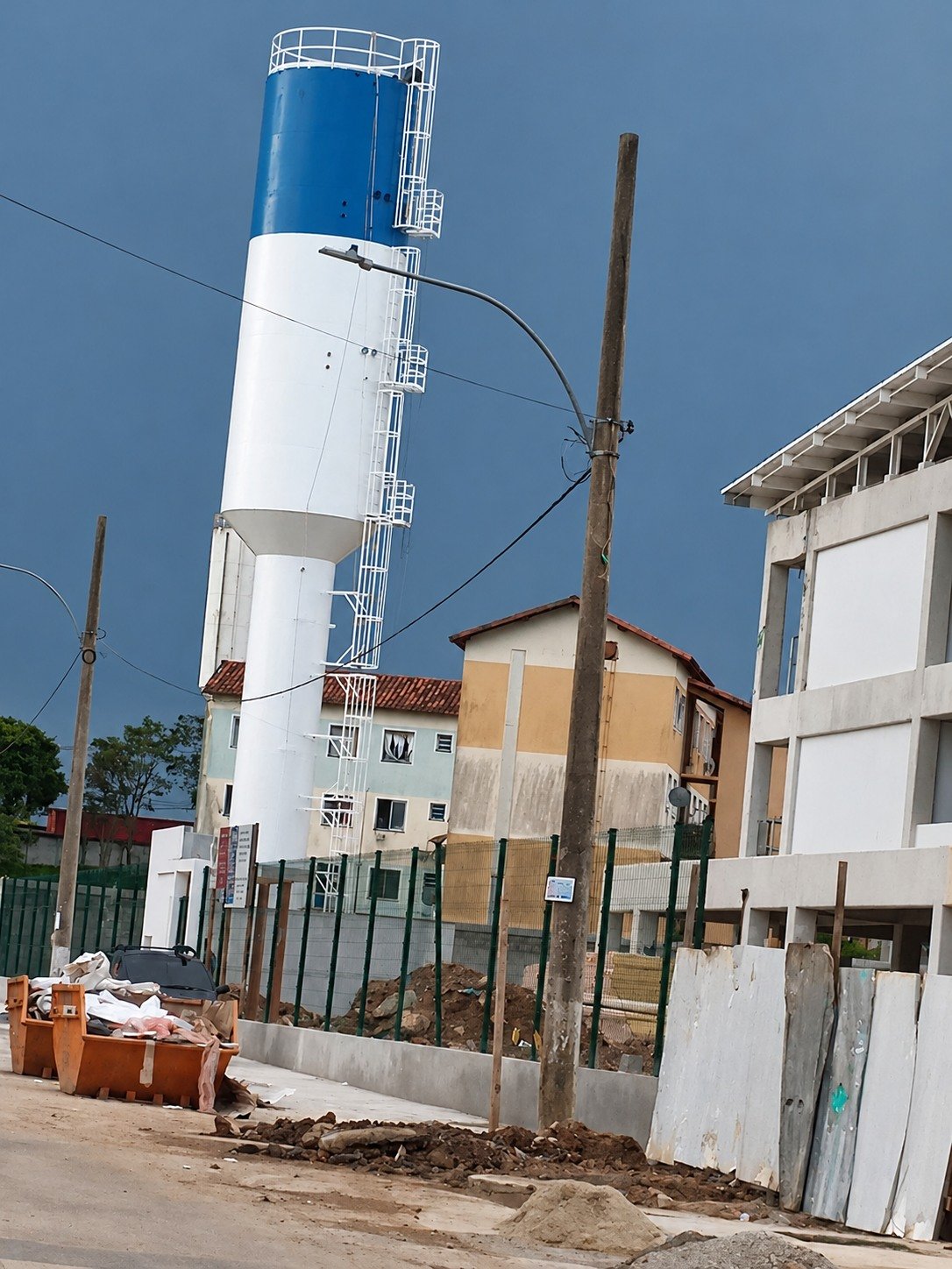 Reservatório tubular vertical com acabamento azul e branco em área urbana